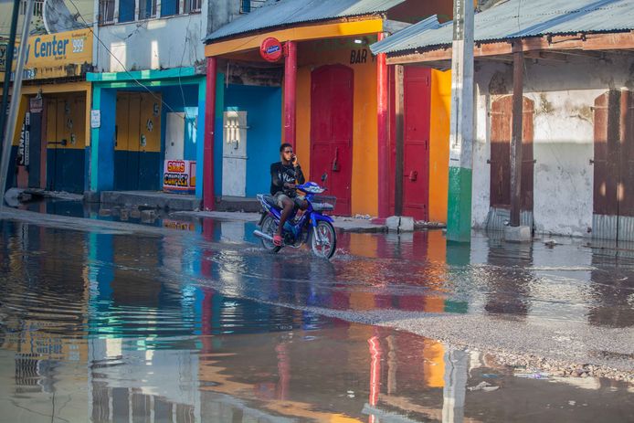 Een man rijdt door een ondergelopen straat in Les Cayes na de aardbeving.