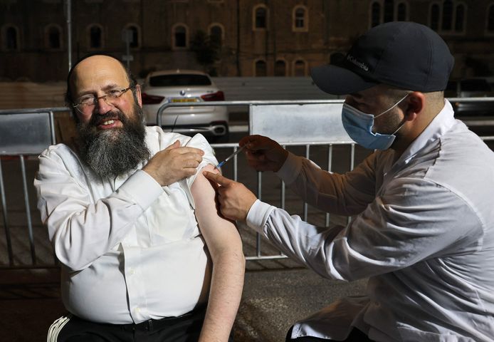 Een Israëlische man krijgt een derde dosis van het coronavaccin ingespoten.