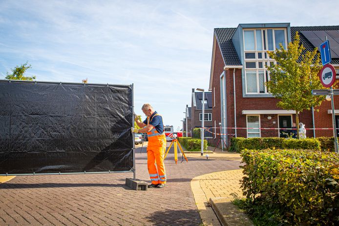 Een forensisch medewerker staat bij de woning die verschillende keren geraakt werd bij de schietpartij. Ondertussen worden zwarte schermen aangebracht om het politiewerk aan het zicht te onttrekken.