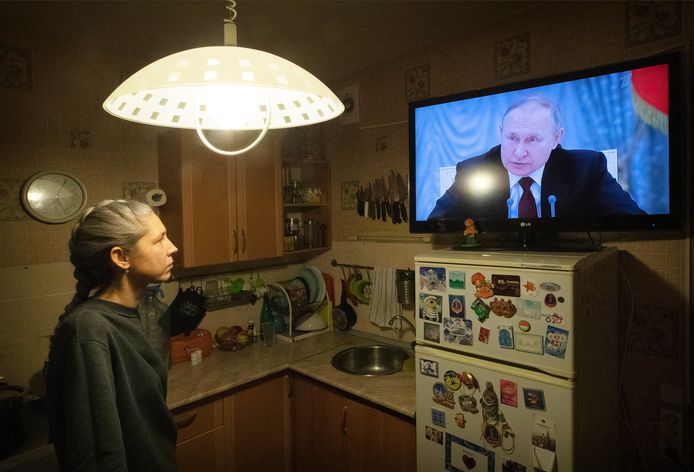Een vrouw kijkt naar de speech van Vladimir Poetin.