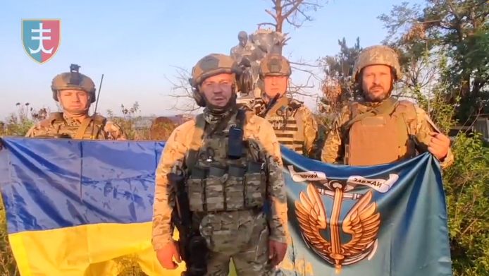 Oekraïense soldaten poseren met de Oekraïense vlag in Oerozjaine.