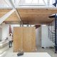 Binnenkijken in een zonovergoten loft, genesteld op de zolder van een oude veeartsenschool