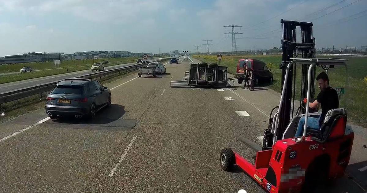 Chauffeur haalt koeltjes heftruck van vrachtwagen om midden op A15 busje met gekantelde aanhanger te helpen - De Gelderlander.