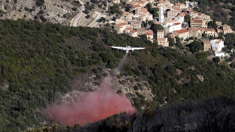 Een blusvliegtuig vliegt over de bossen bij Palasca op het eilandje Corsica.
