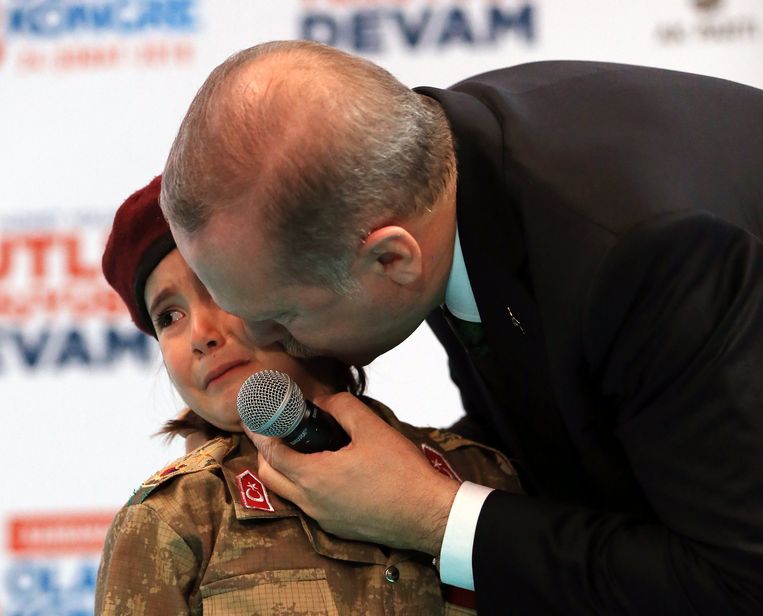 President Erdogan kust een meisje in uniform nadat hij haar bij een congres van de AK-partij op het podium heeft gehaald. Beeld anp
