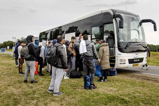 Asielzoekers vertrekken in bussen bij het aanmeldcentrum.