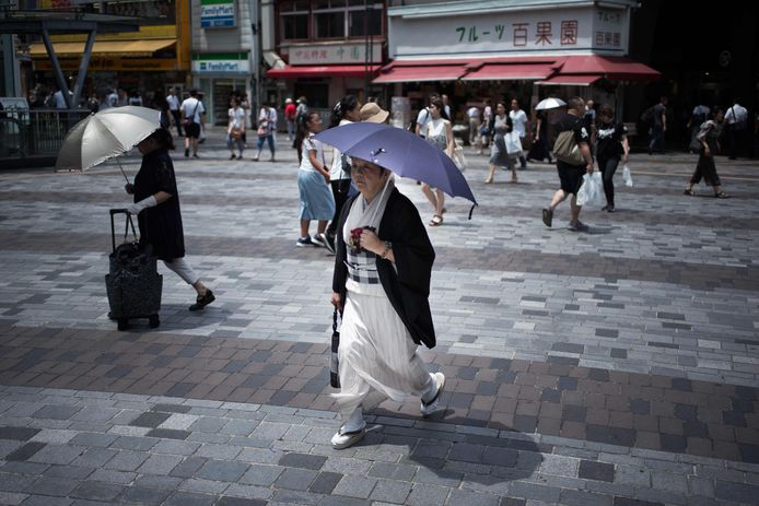 Voetgangers met parasols op straat in Tokyo.
