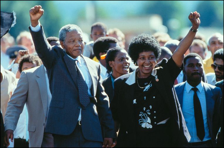 ► Nelson en Winnie Mandela wandelen in 1990 samen de vrijheid tegemoet, nadat Nelson Mandela 27 jaar in de gevangenis had gezeten. Beeld Photo News