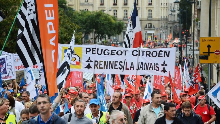 Franse werknemers van Peugoet Citroën protesteren tegen de massa-ontslagen in een fabriek bij Rennes, half september. Beeld AFP