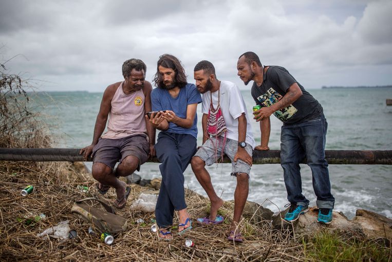 Behrouz Boochani laat inwoners van Papoea-Nieuw-Guinea foto’s zien van zijn geboortestad Ilam, in Iraans Koerdistan.  Beeld LightRocket via Getty Images