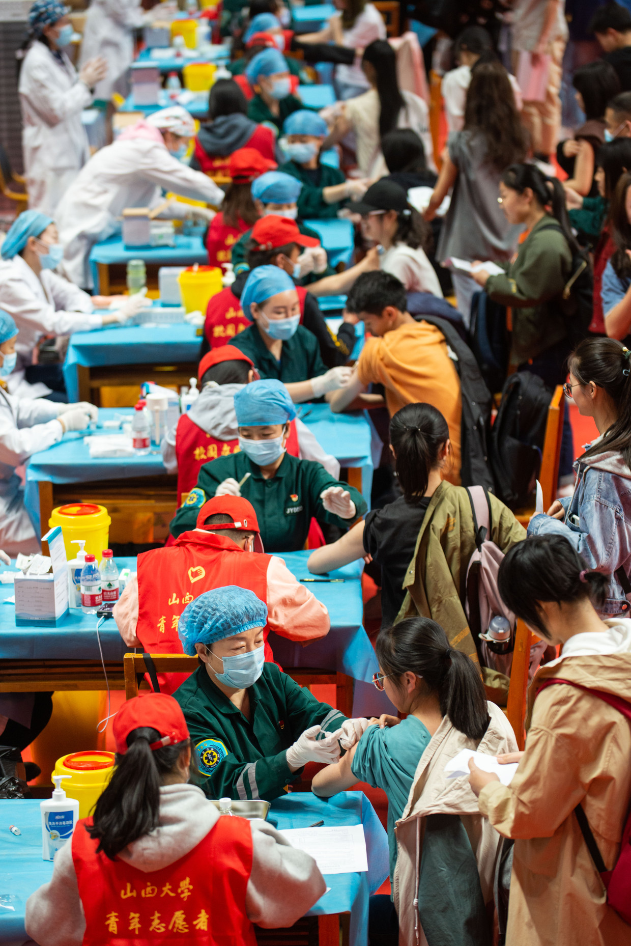 Studenten en docenten van de Shanxi Universiteit in Taiyuan staan in de rij om te worden ingeënt met een covid-19-vaccin. Beeld China News Service via Getty