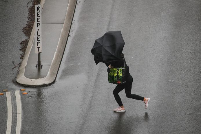 Een voetganger trotseert regen en wind in Sydney.