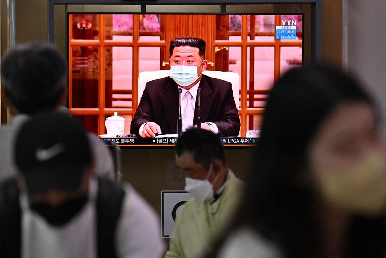 Treinreizigers in Seoul lopen langs een tv-scherm waarop de Noord-Koreaanse leider Kim Jong-un maatregelen aankondigt.  Beeld AFP
