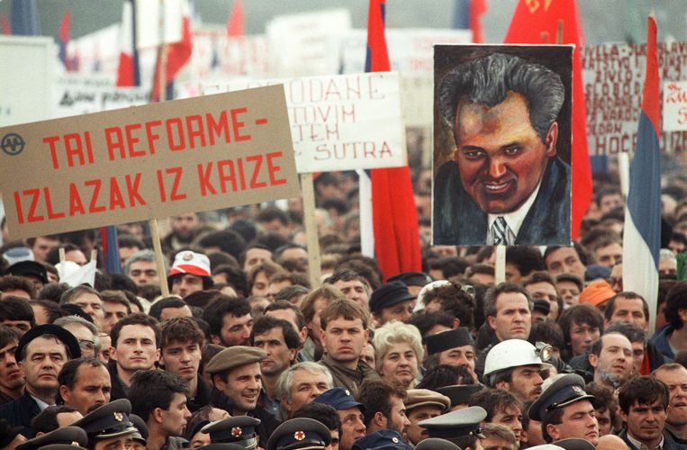 Mensen houden een portret van Slobodan Milosevic omhoog tijdens een betoging in Belgrado in 1988. Beeld AFP