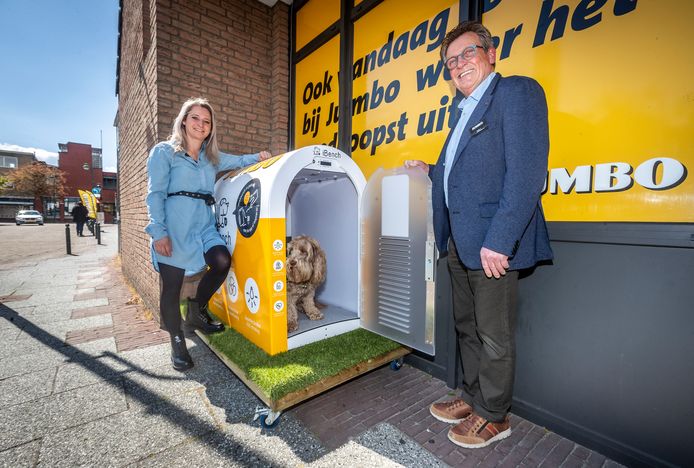 Een supermarkt in Budel heeft een hypermoderne bench in gebruik genomen. Labradoodle Júp test het onderkomen onder toeziend oog van supermarktmanager Wil Hesselberth en Haske de Laat van iBench.