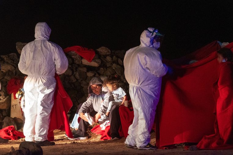 Eem migrantenvrouw en -kind worden opgevangen door Rode Kruis-medewerkers op Fuerteventura, een van de Canarische Eilanden. Beeld EPA