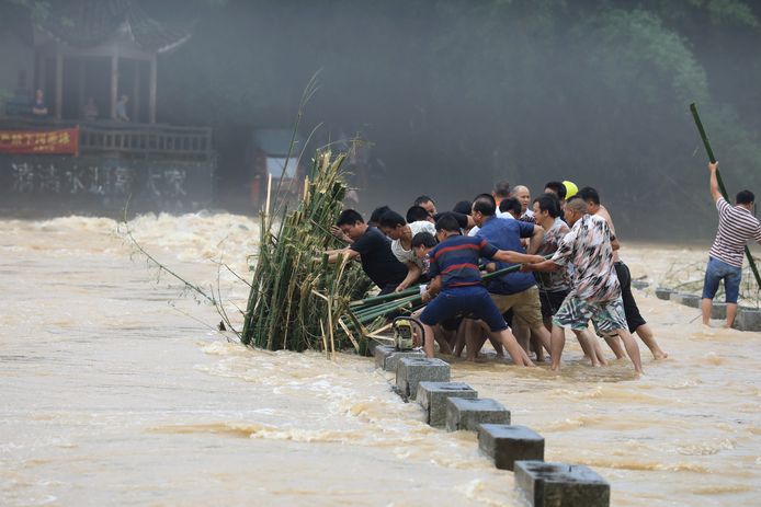 Mannen proberen aangespoelde bamboe te verwijderen van een brug in Liuzhou.