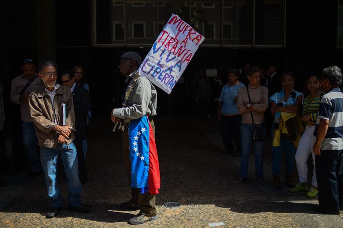 Een man houdt een bord omhoog waarop staat ‘dood aan de tirannie, leve de vrijheid’ in de buurt van de regeringsgebouwen in Caracas.