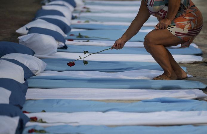 Una donna mette una rosa su un materasso per simboleggiare le vittime del COVID-19.