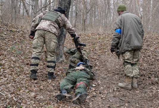 Oekraïense militairen bij de lichamen van dode Russische soldaten na gevechten in  Trostsyanets, op zo'n 400km ten oosten van Kiev.