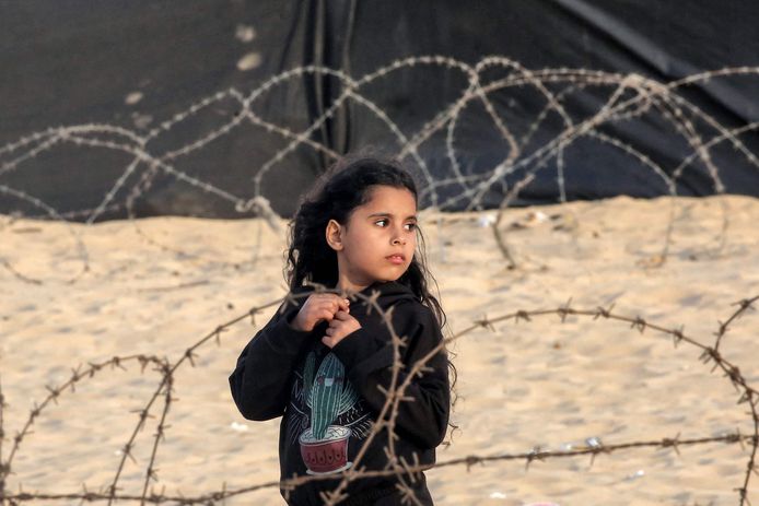 Een meisje staat tussen het prikkeldraad van een vluchtelingenkamp in Rafah. (30/04/2024)