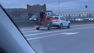 KIJK. Levensgevaarlijke beelden vanop Luikse autosnelweg: man staat zonder beveiliging op rijdende aanhangwagen om zetels te vervoeren