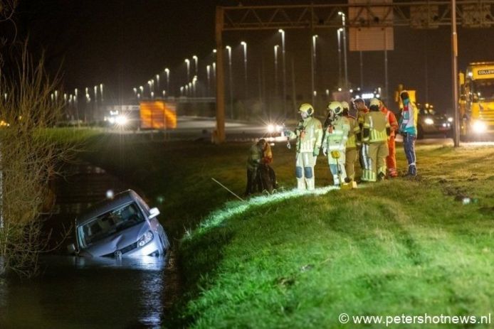 De brandweer overlegt hoe het voertuig uit de sloot gehaald moet worden