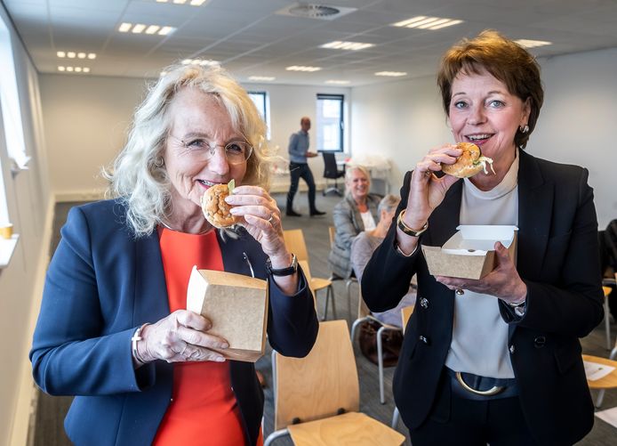 Gedeputeerde Elies Lemkes (lionks) en de Helmondse burgemeester Elly Blanksma zetten hun tanden in veganistische burger van BeefyGreen bij Food Tech Brainport.