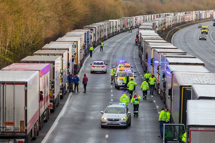 epa08901076 Police and emergency services distribute water and supplies to queues of stationary lorries on the M20 motorway between Ashford and Folkestone in Kent, Britain, 23 December 2020. France closed its border with the UK for 48 hours over concerns about the new coronavirus variant. Lorry drivers must now obtain negative coronavirus tests before they will be allowed to cross by sea and the Port of Dover remains closed to outbound traffic on the morning of 23 December 2020.  EPA/VICKIE FLORES