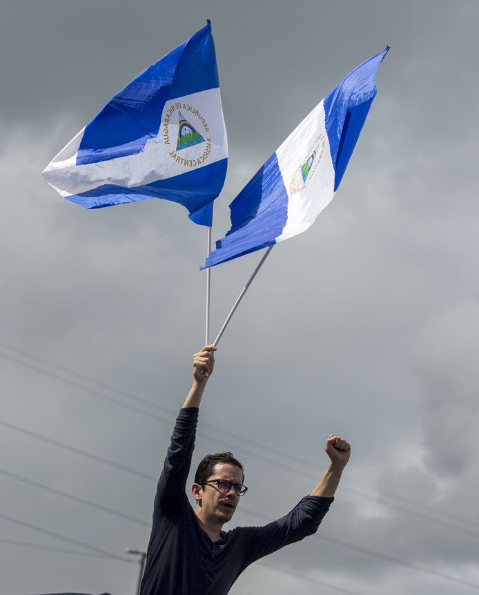 Een burger houdt twee vlaggen van Nicaragua omhoog.