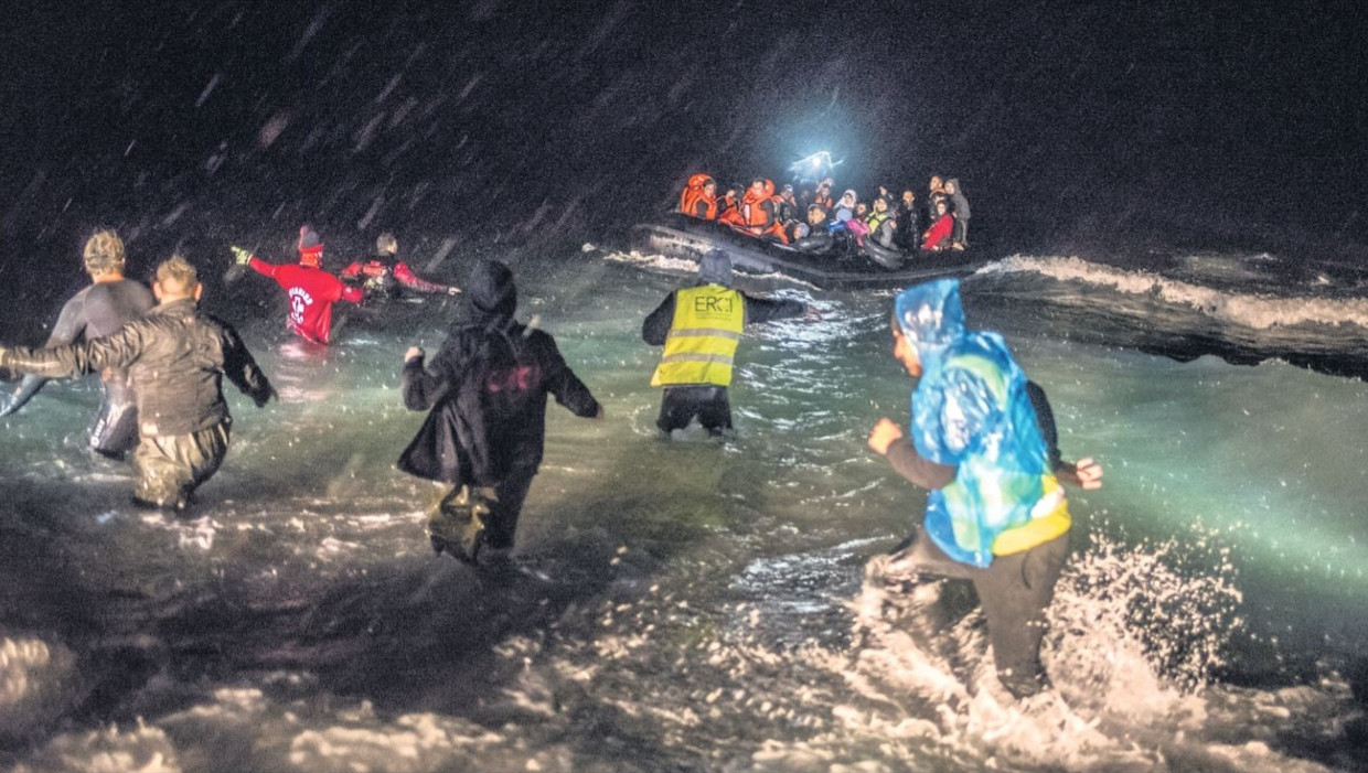 Vrijwilligers proberen vluchtelingen te helpen bij de kust van Lesbos. Beeld Joris van Gennep