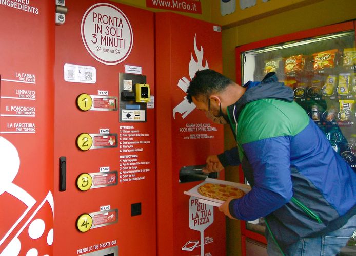 Een Italiaan haalt in Rome de allereerste uit een pizza-automaat.