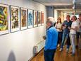 Bij K26 in Oss wordt een expositie geopend met kunst dat is gemaakt met Artificial Intelligence. Op de foto: bezoekers en kunstenaars in gesprek over een van de fotowerken.