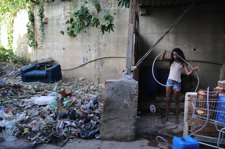 Een meisje vult haar bidon. Water uit de kraan is een luxe in de favela's. Beeld Getty Images