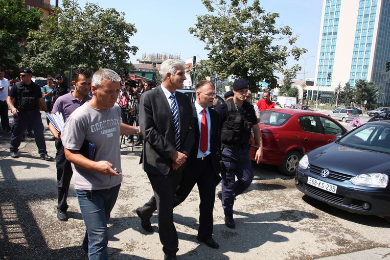 Gouverneur Hashim Rexhepi van de Centrale Bank van Kosovo (met streepjesdas) wordt door politiemensen weggevoerd. Hij wordt verdacht van grootschalige fraude (Reuters) Beeld REUTERS