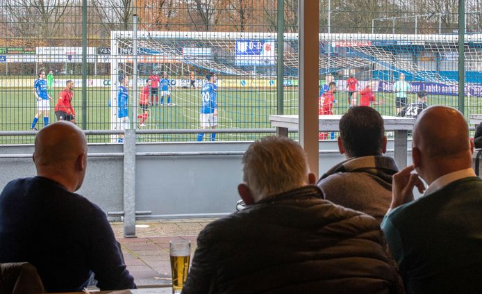 Vanuit de kantine van GVVV in Veenendaal slaan supporters een wedstrijd van de hoofdmacht gade. Want langs de lijn staan mag niet, maar vanuit de kantine de wedstrijd volgen wél.