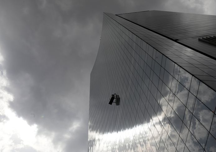 In Mexico-City wast een glazenwasser de ramen terwijl de dreigende lucht boven hem een regenbui aankondigt. Foto Henry Romero