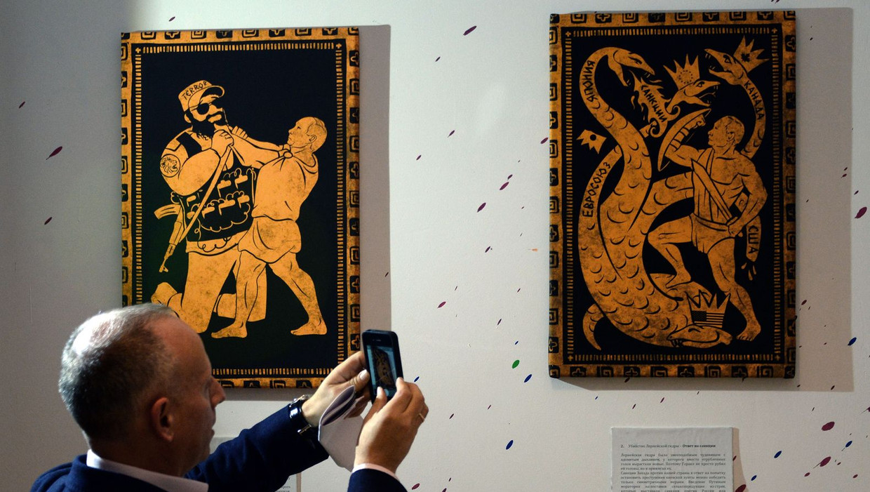 Een bezoeker maakt foto's tijdens de tentoonstelling 'De 12 werken van Poetin' die gisteren te zien was in Moskou. Beeld afp