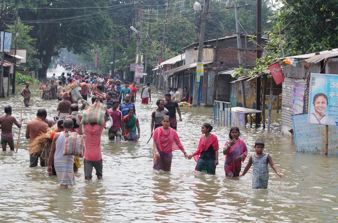 Inwoners waden door het water na een overstroming in West-Bengalen, India.