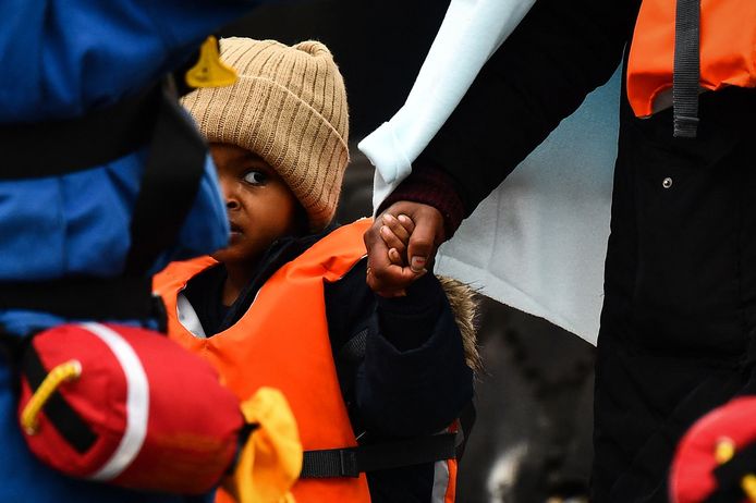 Een kind houdt de hand vast van een volwassene terwijl Britse kustwachten hen van boord helpen, nadat ze op zee waren opgepikt toen ze probeerden het Kanaal over te steken.