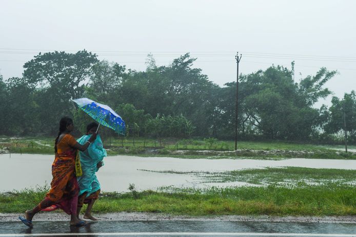 Twee vrouwen met paraplu haasten zich naar een veilig onderkomen nu cycloon Amphan aan land gaat komen.