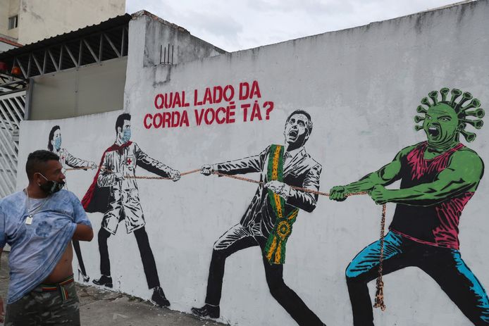 Het coronavirus en de Braziliaanse president touwtrekken tegen gezondheidsmedewerkers met mondkapjes op op een muurschildering in Brazilië, het zwaarst getroffen land ter wereld.