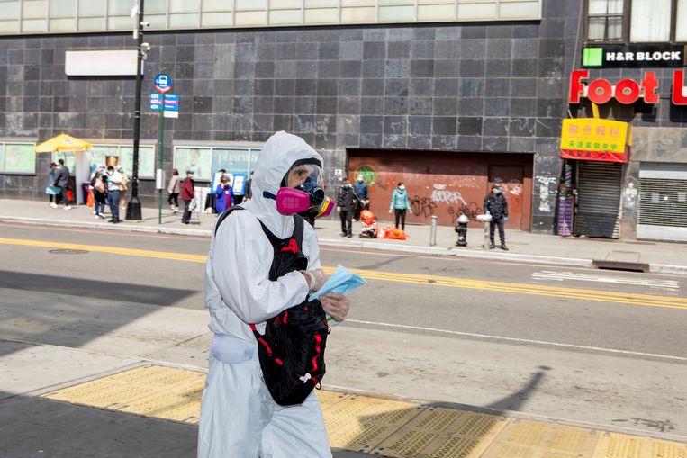 Meneer die maskers en handschoenen uitdeelt in Main street, de hoofdstraat van Chinatown in Flushing Queens. Beeld Chantal Heijnen