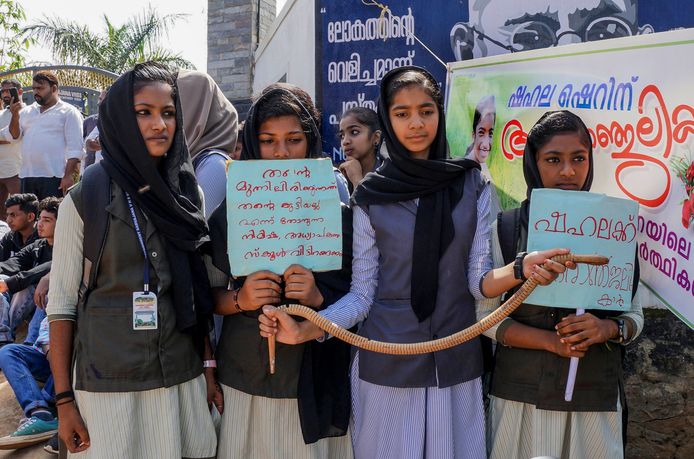 Meisjes demonstreren met een nepslang en protestbordjes.