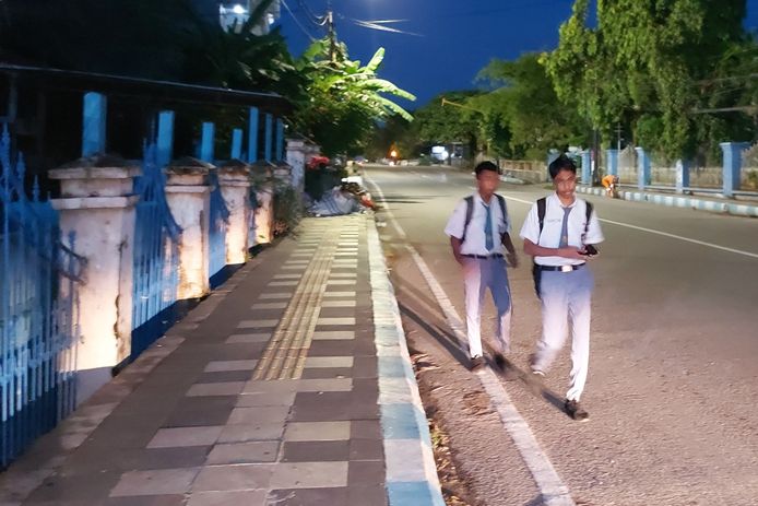 Dua siswa dalam perjalanan ke sekolah melewati jalanan Kupang yang masih gelap dan sepi.