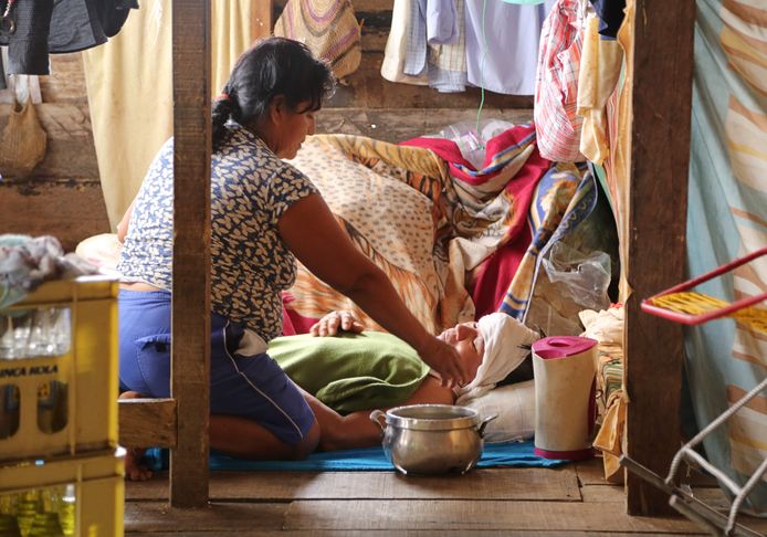 Een familielid verzorgt een zieke man in Iquitos, Peru. Beide dragen geen mondkapjes.
