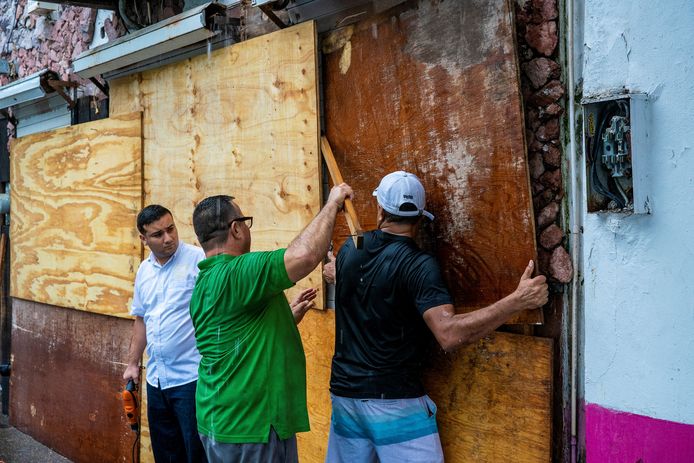 Mannen plaatsen houten planken voor hun winkelramen en -deuren in Puerto Vallarta, Mexico, in afwachting van orkaan Lidia.