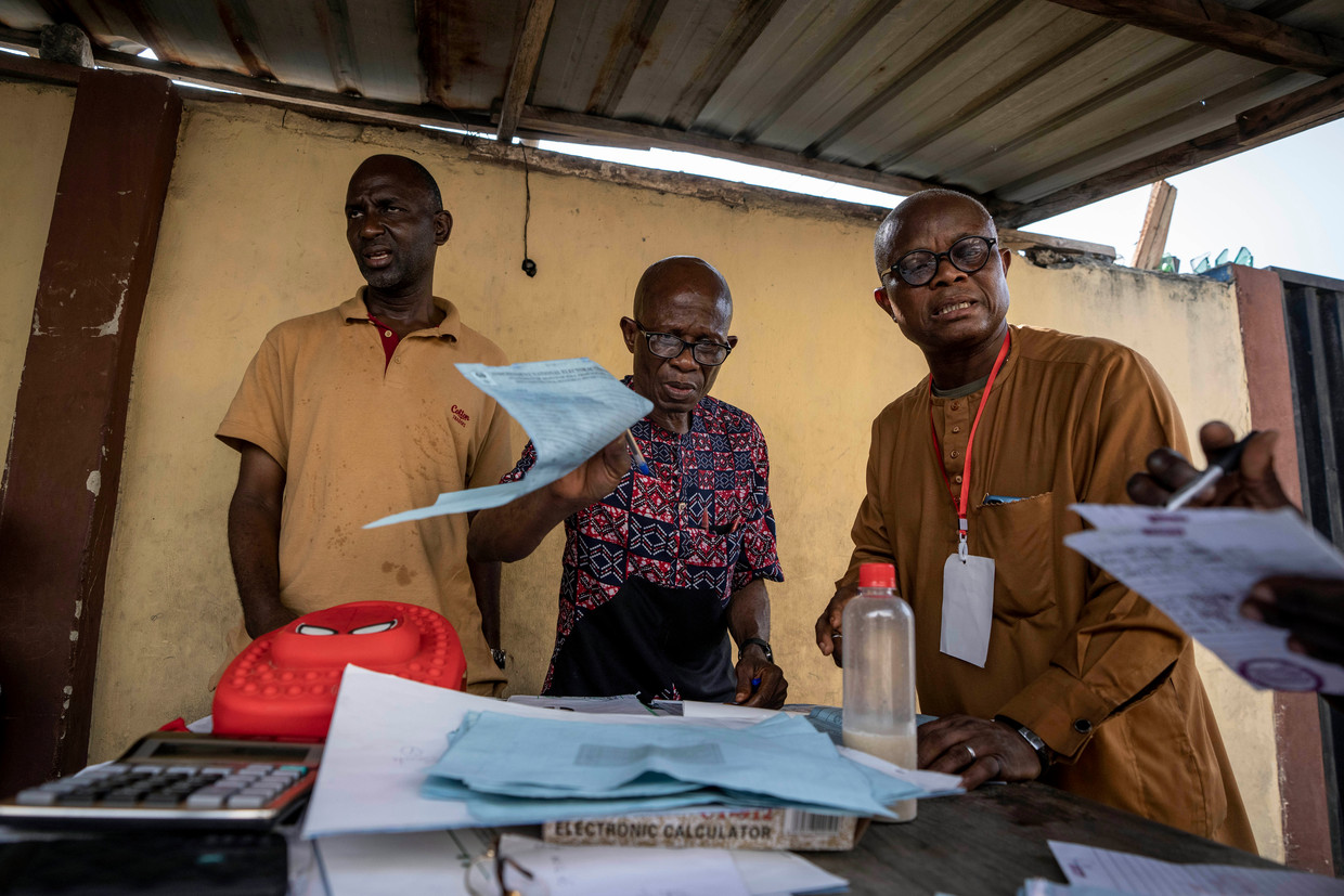 Medewerkers van een stembureau in de Nigeriaanse havenstad Lagos tellen stembiljetten met de hand. De verkiezingen waren zaterdag, maar het stemmen ging zondagochtend nog door, na veel logistieke problemen.  Beeld AP