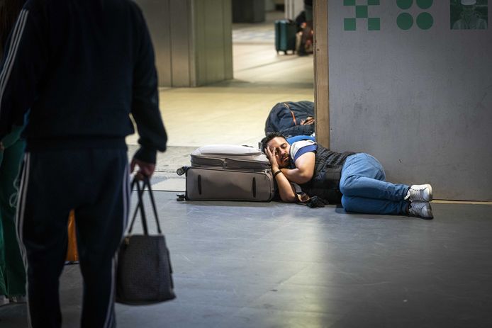 Een slapende reiziger op Amsterdam Centraal.