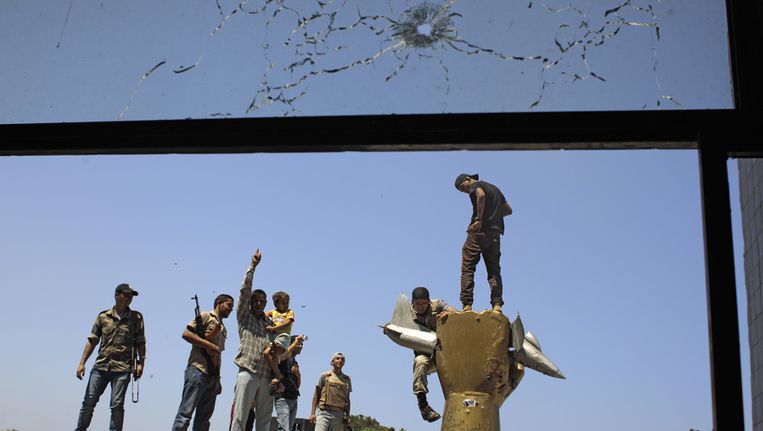Libiërs klauteren op een monument in het hoofdkwartier van Kadaffi. Beeld ap